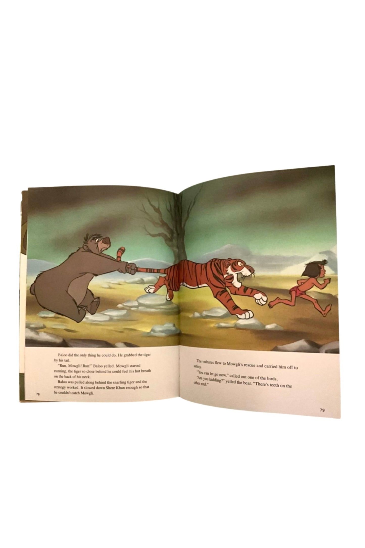 Open book showing a colorful llustration of Mowgli and his friends running