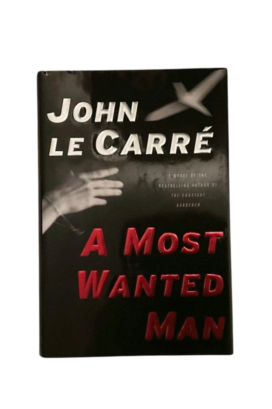 Book cover of 'A Most Wanted Man' by John Le Carre with a black background and red text.