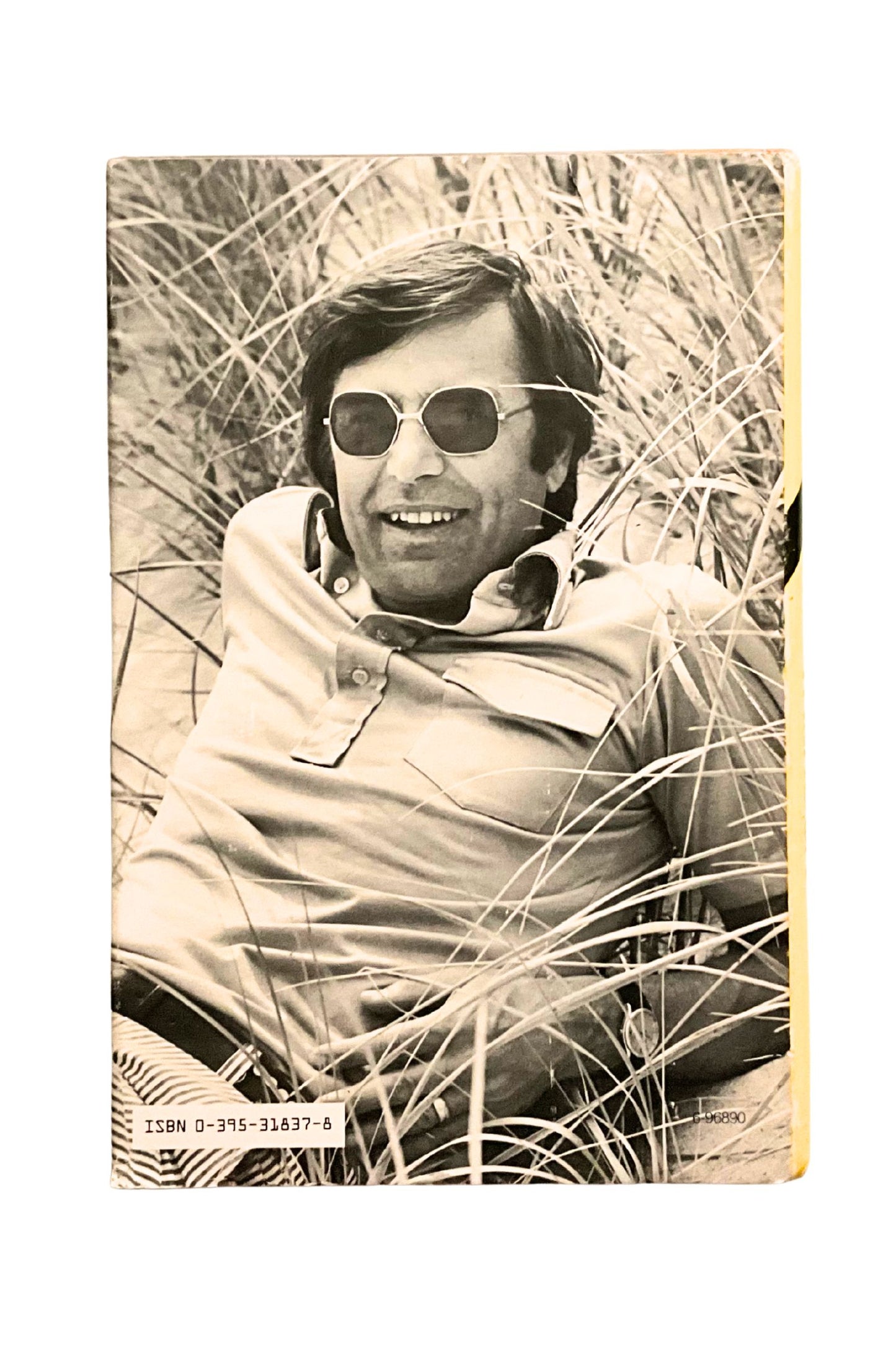 Vintage-style black and white photo of the author sitting in tall grass wearing sunglasses.