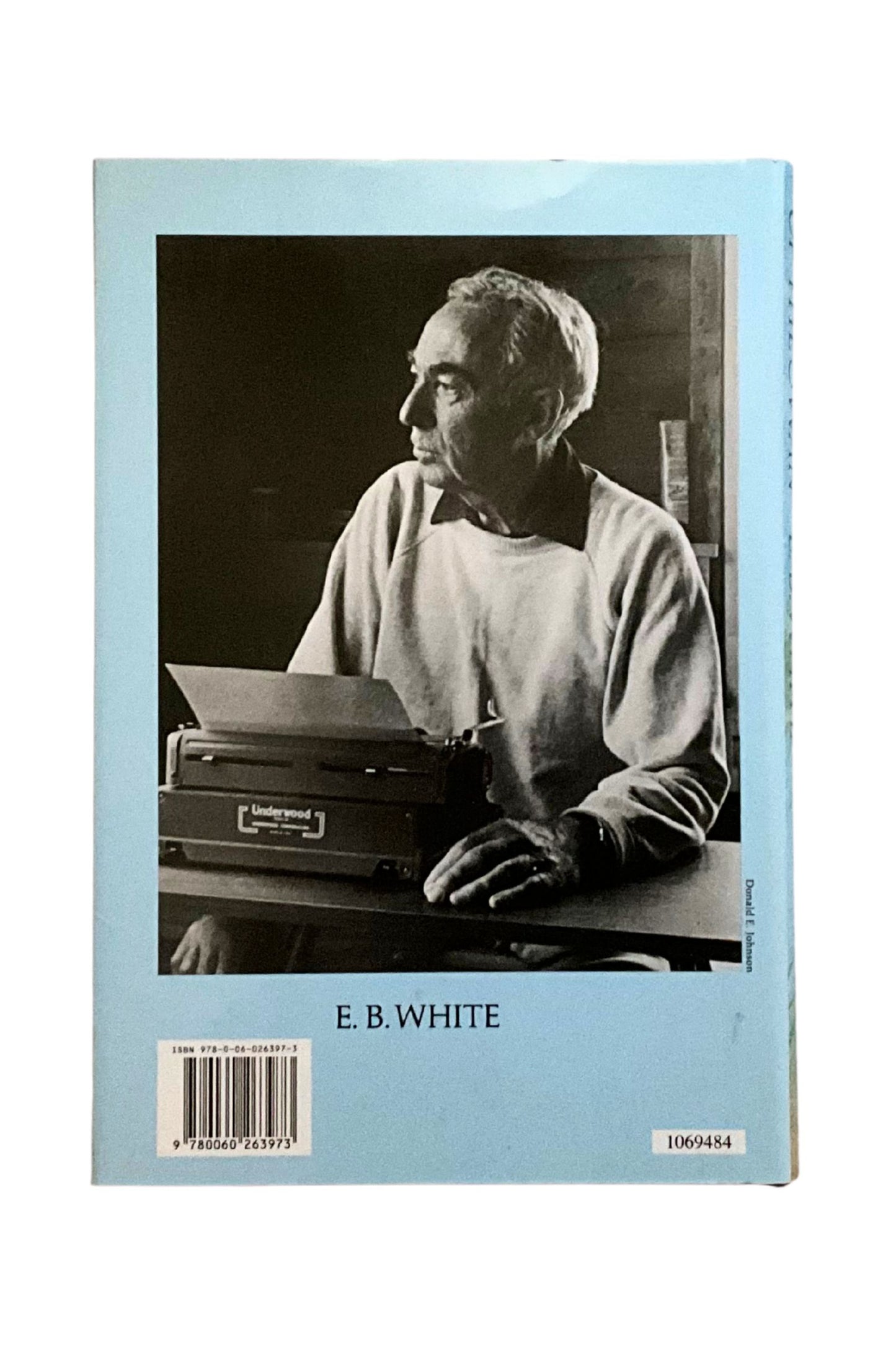 Back cover of ‘The Trumpet of the Swan’ with a black and white photo of E.B. White at a typewriter on a light blue background